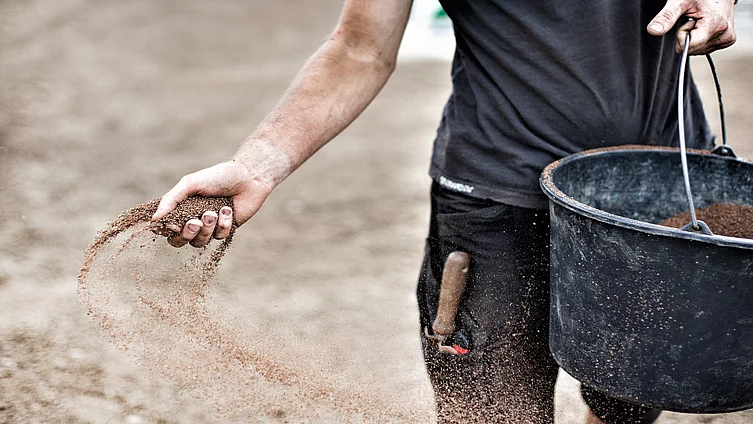 A person is holding a bucket from which they are sowing