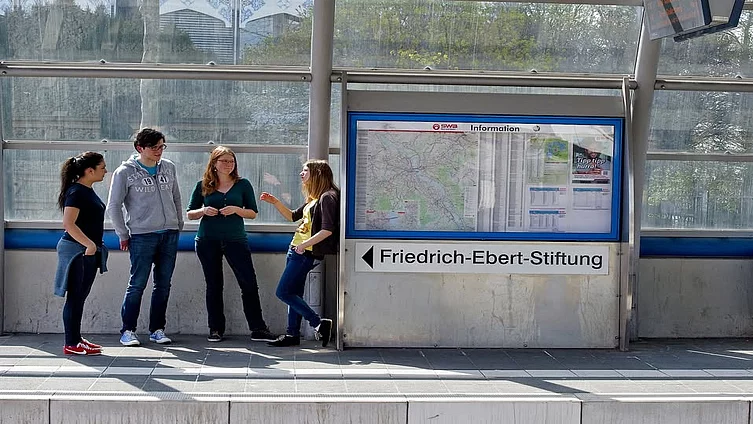 Four young students are talking at a train station in Berlin.
