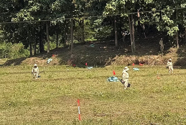 Deminers searching a marked field in Vientiane, Lao People’s Democratic Republic.