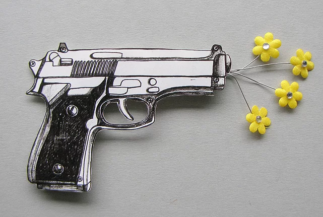 Silver pistol with yellow plastic pellets on a white background