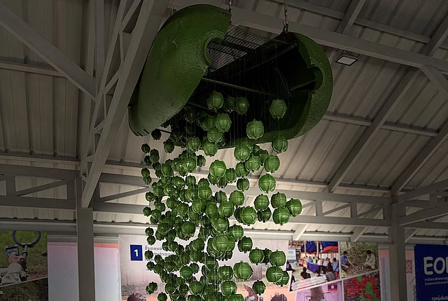 Exhibit of green bomblets falling from an opened cluster munition casing.