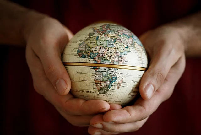 A pair of hands holding a small globe displaying the continent of Africa